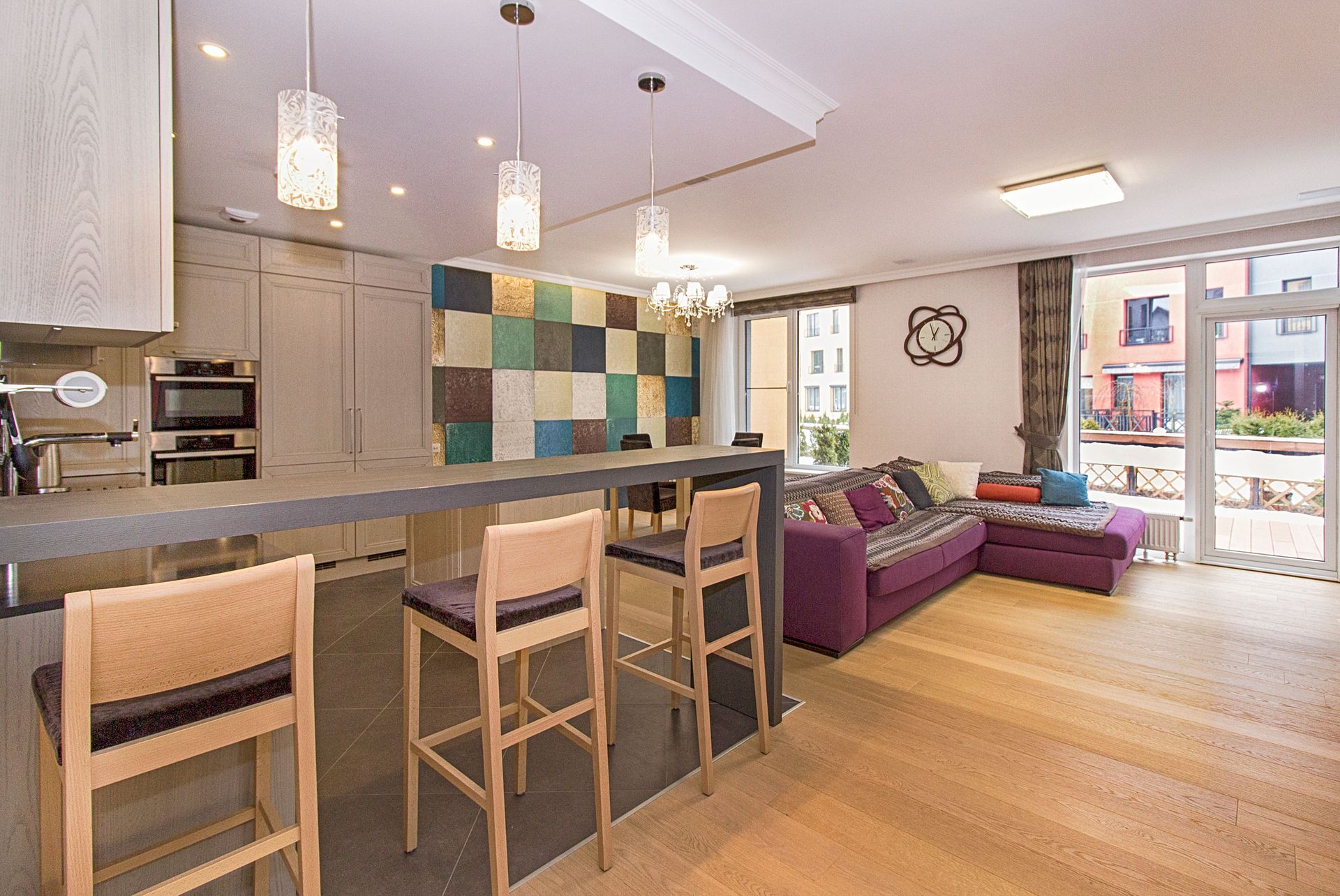 Stylish open-plan kitchen and living room with modern decor and ample lighting.